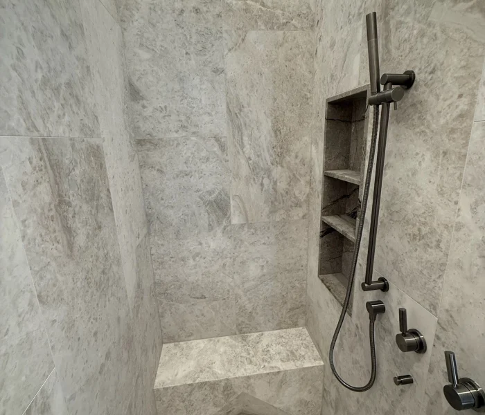 Stone shower with built-in niche and modern rainfall fitting.