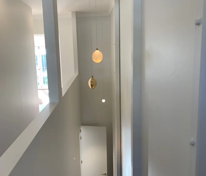 Narrow hallway with soft glowing wall lights and clean design.