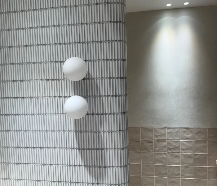 Curved feature wall with twin globe lights and textured tiles.